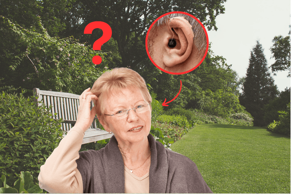 Old woman confused about hearing aids, standing in a park